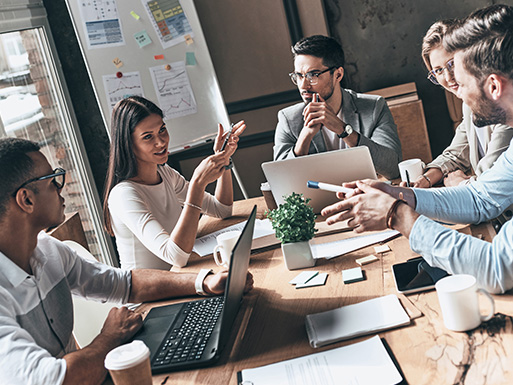 group of professionals having a meeting around a table with laptops and documents discussing three important ideas