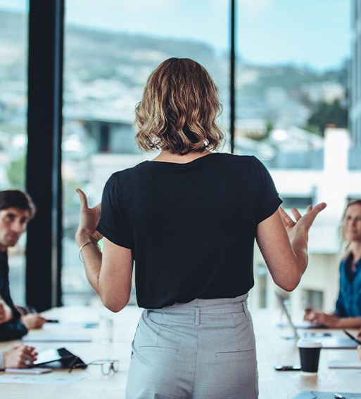 woman presenting in a modern office meeting with three people listening attentively and discussing ideas