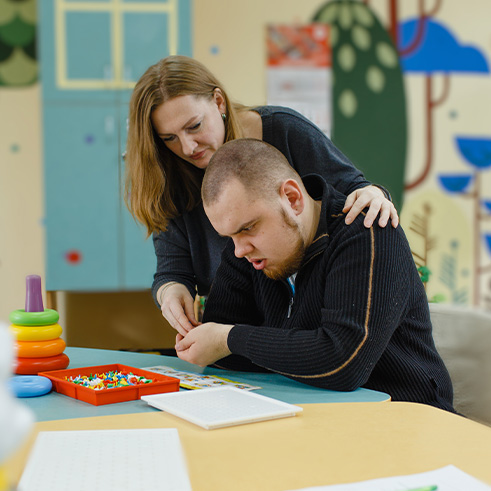 mother helping daughter with painting activity while she wears headphones enjoying creativity time
